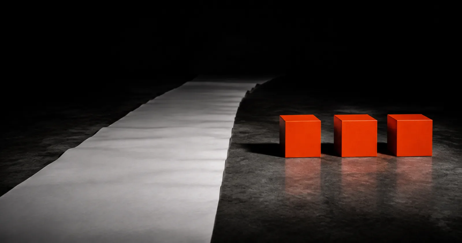 Three identical orange cubes lined up beside a long white strip running into the dark